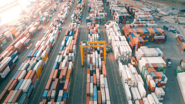 Cargo containers in busy port, aerial hyperlapse. Shipping harbor, logistics, loading and unloading of ships. Export and import of goods