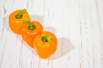 Three orange bell peppers on a white background (top view).