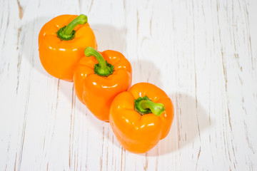 Three orange bell peppers on a white background (top view).