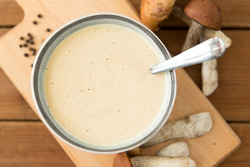 food cooking, eating and culinary concept - mushroom cream soup in bowl on wooden cutting board