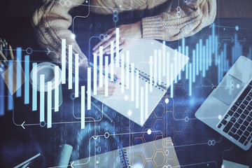 Forex graph on hand taking notes background. Concept of research. Double exposure