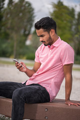 Male model sitting in a garden using the phone