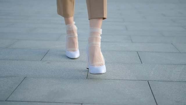 Legs walking. Determination and emancipation. Female feet on heels and in trendy nylon socks