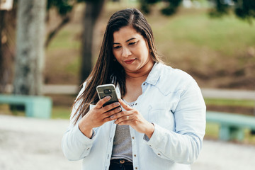 Portrait of beautiful plus size woman using her smartphone outdoors