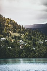 Schöner See mit Häusern auf einem grünen Hügel im Hintergrund