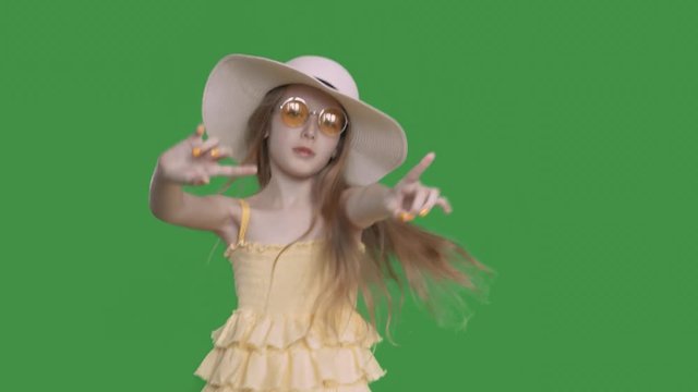Pre-teen pretty girl in yellow dress and hat is dancing ang singing, keyed green screen. She is in summer clothes on her happy vacations. Alpha channel transparent background
