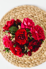 Fototapeta na wymiar Stunning composition of colorful roses in a glass vase on a wicker napkin