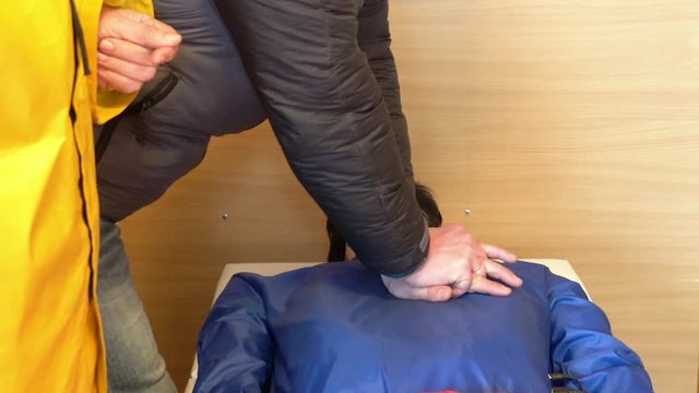 First aid courses for people. Man learns to make compression heart massage on mannequin in the presence of an instructor, hands closeup.