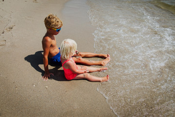 boy and girl play with water on beach vacation, kids relax and have fun