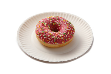 Sweet doghnut in pink glaze decorated with sprinkles on a paper plate isolated on a white background