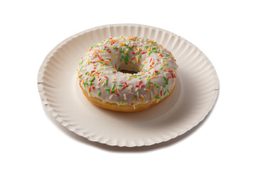 Sweet doghnut in white glaze decorated with sprinkles on a paper plate isolated on a white background