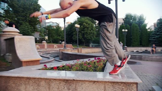 Acrobatic men performing parkour trick - a man jumping on the border and perform a flip