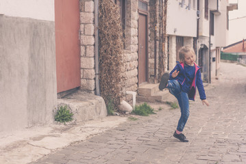 Fototapeta na wymiar Little girl practising kicks on a street