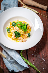 Tagliatelle with seafood. Traditional Italian pasta with shrimp, Basil in cream sauce on a white plate.