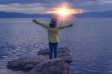 Triumphant little girl on a lakeshore