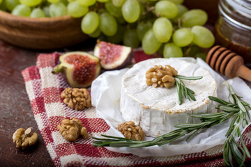 Whole camembert on red checkered napkin in cage with rosemary, walnut, grapes and date, gastronomic peasure