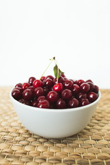 A plate full of fresh cherries on a natural wicker napkin