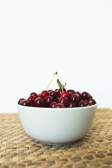 A plate full of fresh cherries on a natural wicker napkin