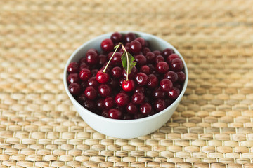A plate full of fresh cherries on a natural wicker napkin