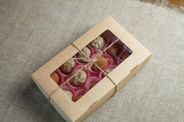 Homemade candy in the form of balls of dried fruit with walnut and cocoa powder in the box on a linen napkin on the table. Healthy food without sugar and gluten.