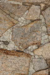 The texture of the sidewalk of chaotic granite stones of different colors with many cracks