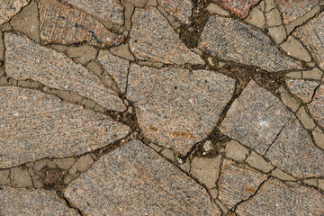 Obraz premium The texture of the sidewalk of chaotic granite stones of different colors with many cracks