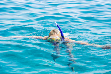 summer vacation time activities concept photography of snorkeling girl in mask and tube with face under Red sea water blue slightly wavy surface 
