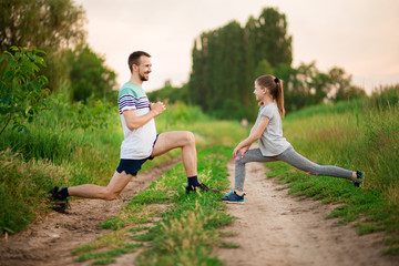 Athletic young father and little daughter do exercises in stadium. Healthy lifestyle