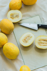 Melon berries and sliced juicy melon halves on the kitchen table .