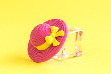Close up of pink sun hat and ice cube refreshment abstract isolated on yellow.