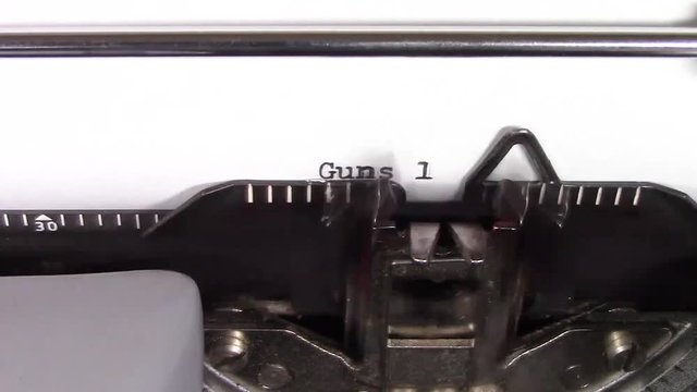 A close up video of the words " Guns 101 " being typed on white paper in an old manual typewriter. Shot in macro.