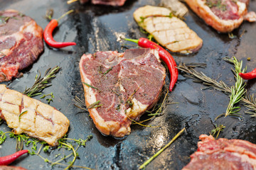 Cooking beef steak on rib-in bone and duck breast closeup