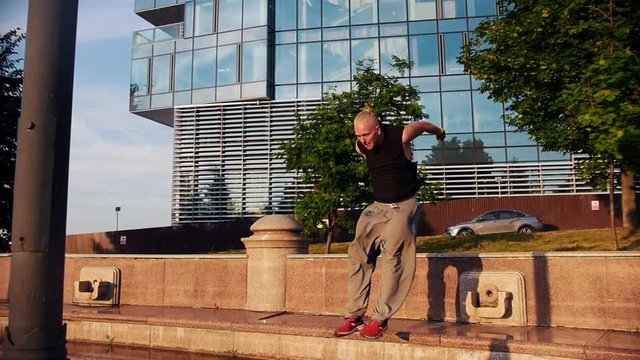 Acrobatic blonde man running up and overcome obstacles with parkour tricks