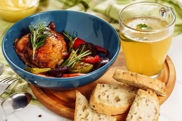 Barbeque Vegetables Chicken and Mustard Broth. Roast Grilled Bird Hind Quarter Meat, Zucchini and Paprika Decorated Rosemary in Bowl on Wooden Board with Piece of Bread and Sauce in Glass Closeup