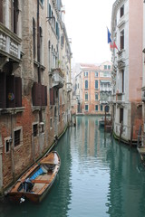 Fototapeta na wymiar Canal in an overcast Venice with a parked boat