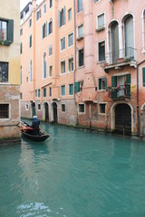 Fototapeta na wymiar Gondolier on their Gondola cruising through a canal in Venice