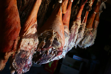 Smoked legs of ham in smokehouse. Whole ham hanging from the ceiling in farm. healing and drying of hams from Iberian pigs