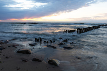 baltic sea with old breakwaters at long shutter speed at sunset