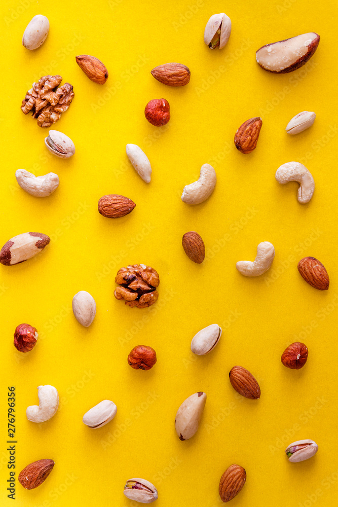 Sticker A variety of nuts are scattered on a yellow background. Flat lay. View from above. Copy space.