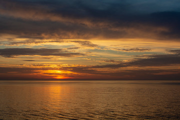 Naklejka na ściany i meble Beautiful fiery sunset sky on the beach. Sunrise over the sea and beautiful cloudscape.