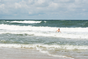Children swim in the sea on the big waves in a storm. Dangerous swimming during a storm on the beach.