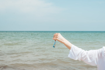 A woman holds a bottle with a message near the sea, ocean.