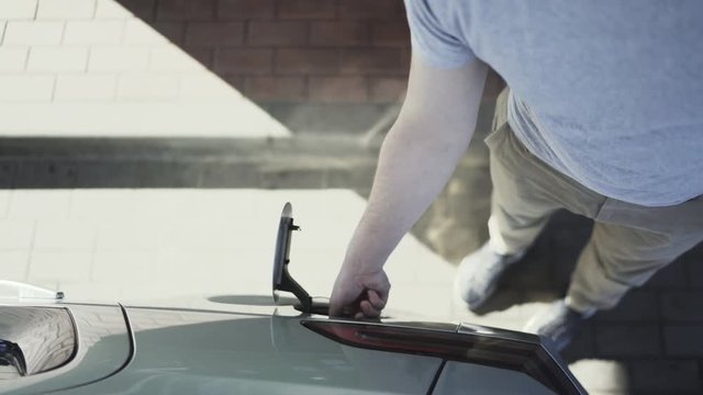 Man fills his car with gasoline at night at gas station