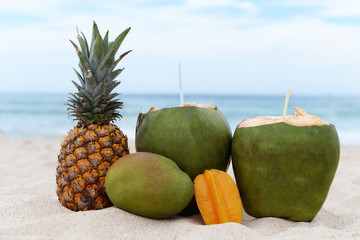 tropical fruit green coconut young with anannas carom and mango on holiday on the sea ocean on the beach on the sand to advertise tourism