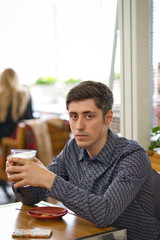 man sitting in cafe and drinking coffee, large latte in man's hands