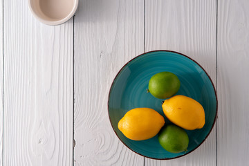 Fake artificial lemon lime fruit on plate on old white farmhouse table