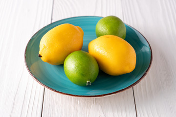 Fake artificial lemon lime fruit on plate on old white farmhouse table