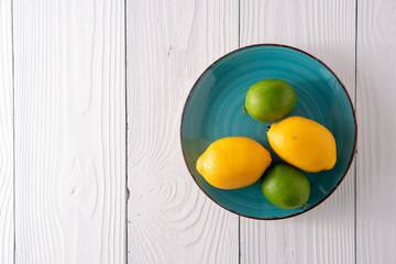 Fake artificial lemon lime fruit on plate on old white farmhouse table