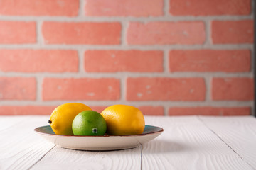 Fake artificial lemon lime fruit on plate on old white farmhouse table