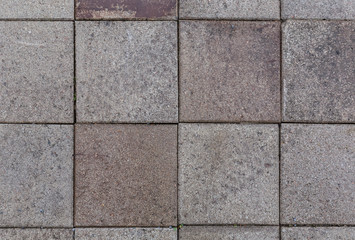 Close-up of a bit dirty and weathered square paving stones or blocks outdoors viewed from above. High resolution full frame textured background.
